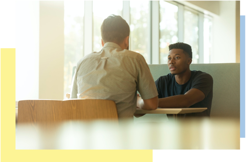 two men sitting at a table talking